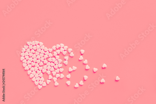 Pink heart shaped candies on a soft pink paper background. Broken heart or pearts gethering love concept. Copy space included.