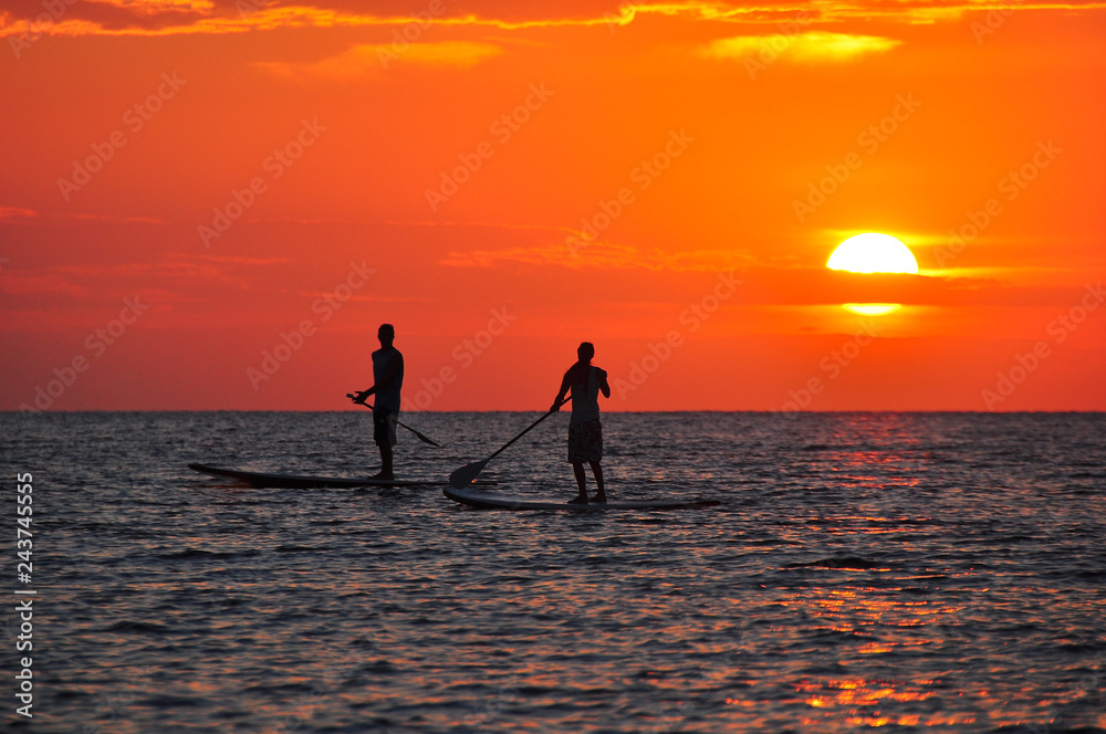 Personas practicando paddle surf al atardecer en Ibiza 