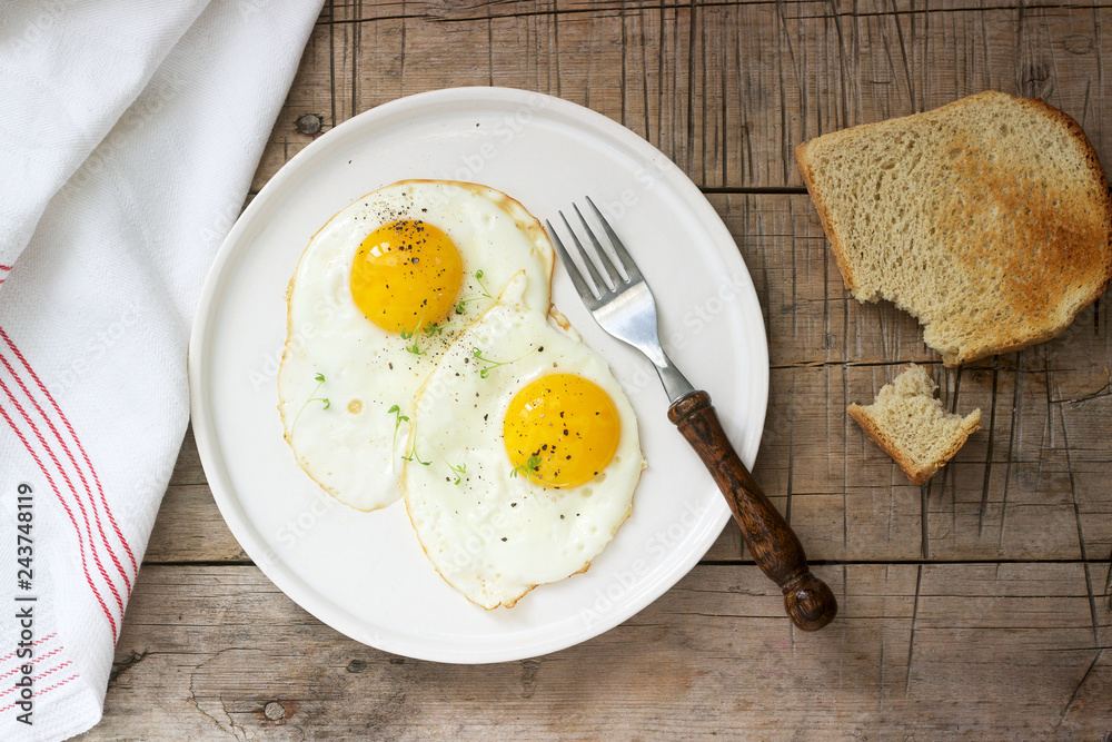 Breakfast of fried eggs, bread toasts and coffee on a wooden table. Rustic style.