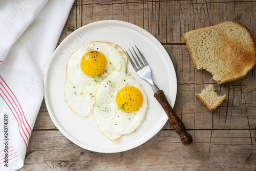 Obraz na płótnie Breakfast of fried eggs, bread toasts and coffee on a wooden table. Rustic style. w salonie