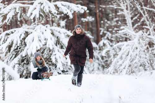 Beautiful couple on sledge having fun, winter snow day