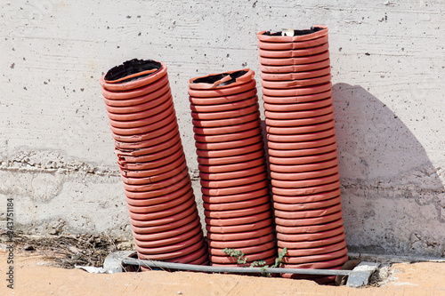 Red orange corrugated sheath for electric cables, on a building construction site
