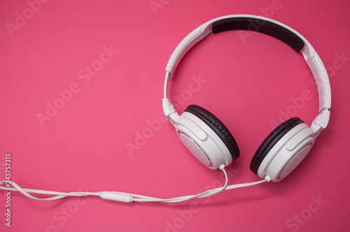 closeup of white headphones on pink background