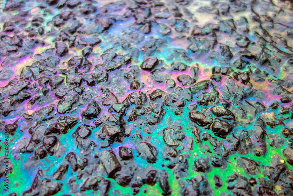 Obraz premium Rainbow Liquid Petrol Pollution Leak on Asphalt Road