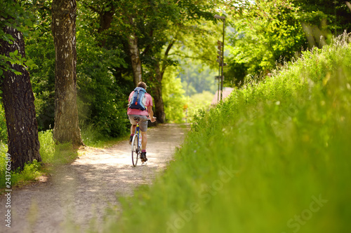 Sportive man cycling in sunny park in hot summer day. Switzerland, Europe