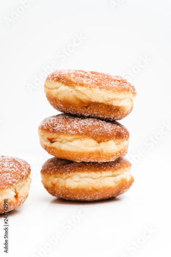 German or Austrian donuts filled with jam and dusted with cinnamon sugar, so called Krapfen, Berliner or Pfannkuchen, traditionally eaten at carnival or New Year's Eve, isolated on white background