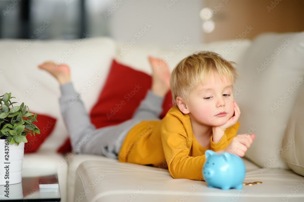 Little boy looks on moneybox and plans of what he can buy. Little boy looks on moneybox and plans of what he can buy.