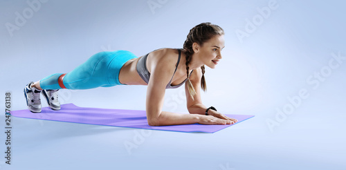Sport. Muscular woman on a plank position use fitness gum. Muscular and strong girl exercising. Fitness exercising with expander. 