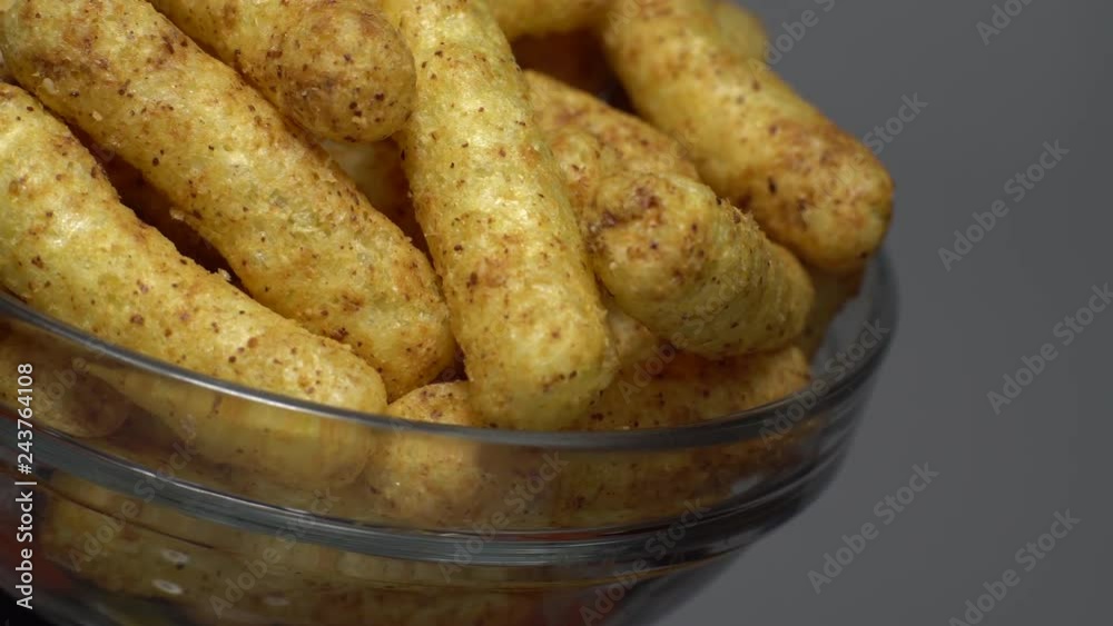 Corn puffs. Rotation. Close up. Puffcorn with peanut flavor. Corn snacks in a bowl. Puffed corn chips. Grey background. Studio shot. Unhealthy diet concept. Junk food concept. Corn puffs. Rotation. Close up. Puffcorn with peanut flavor. Corn snacks in a bowl. Puffed corn chips. Grey background. Studio shot. Unhealthy diet concept. Junk food concept.