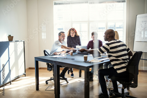 Young designers discussing paperwork together during an office m © Flamingo Images