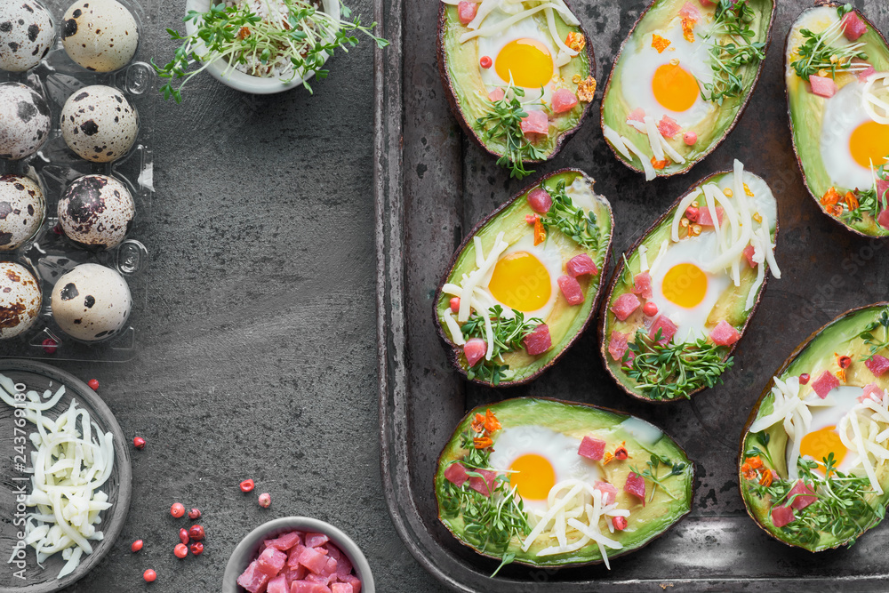 Keto diet dish: Avocado boats with ham cubes, quail eggs, cheese and pepper on dark