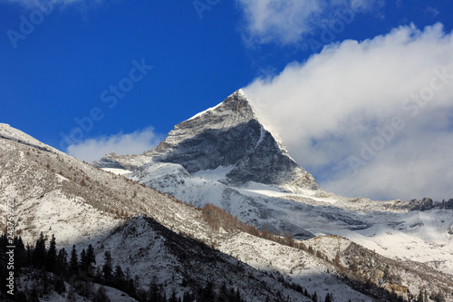 Four Girls Mountain National Park in Sichuan Province, China. ShuangQiao Valley Scenic Area, Snow Capped Jagged Mountains with clouds forming at the summit. Blue Sky, Snow Mountains, Siguniangshan