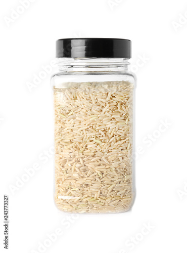 Jar with uncooked brown rice on white background