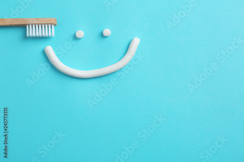 Fototapeta Naklejka Na Ścianę i Meble -  Smiling face made of toothpaste, brush and space for text on color background, top view