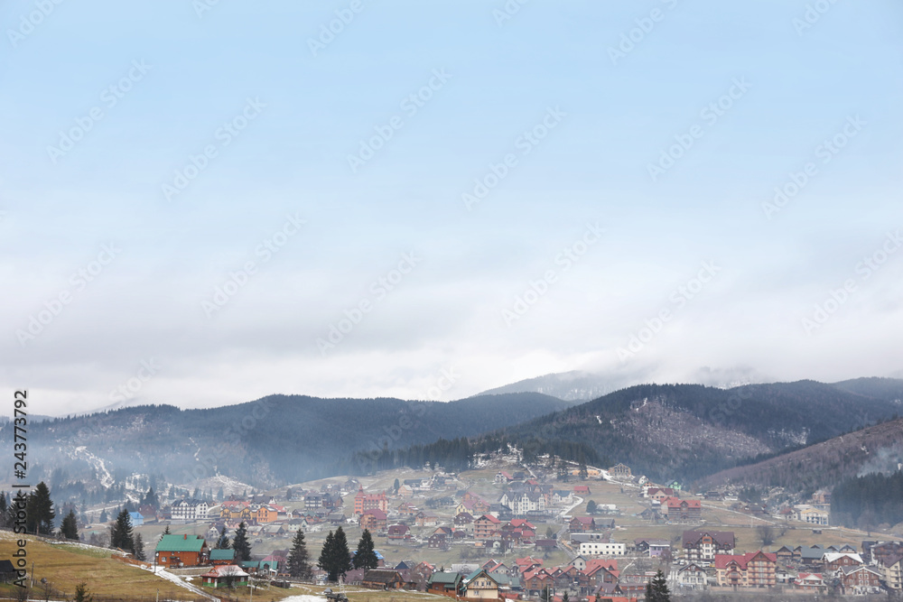 Beautiful winter landscape with buildings and forest on hills