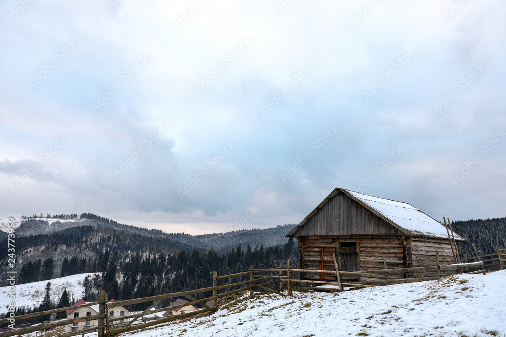 Winter landscape with old hut on snowy slope
