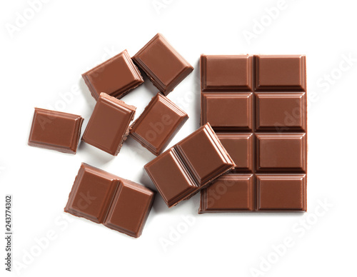 Pieces of tasty milk chocolate on white background, top view