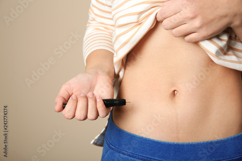 Woman doing insulin injection in stomach, closeup. Diabetes disease photo