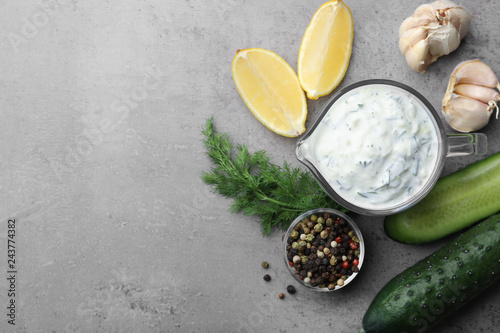 Cucumber sauce with garlic, lemon, dill and pepper on grey background, top view. Space for text