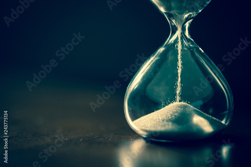 Hourglass as time passing concept for business deadline, urgency and running out of time. Sandglass, egg timer on dark background showing the last second or last minute or time out. With copy space.