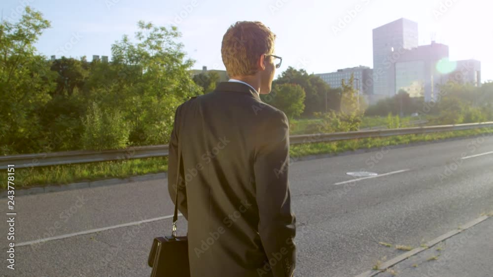 SLOW MOTION, LENS FLARE, CLOSE UP: Unrecognizable young man in a black suit casually walking to a business meeting in the sunny city. Carefree businessman walking home after quitting his stressful job SLOW MOTION, LENS FLARE, CLOSE UP: Unrecognizable young man in a black suit casually walking to a business meeting in the sunny city. Carefree businessman walking home after quitting his stressful job