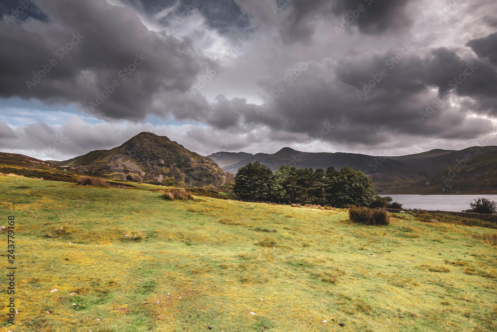 Scenic landscape of Cumbria,Uk.Moody sky above mountain peak, trees, grass, hill and lake.No people and copy space.