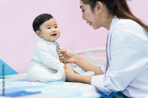 Asian doctor woman examining a little boy by stethoscope in hospital. Medicine and health care concept..