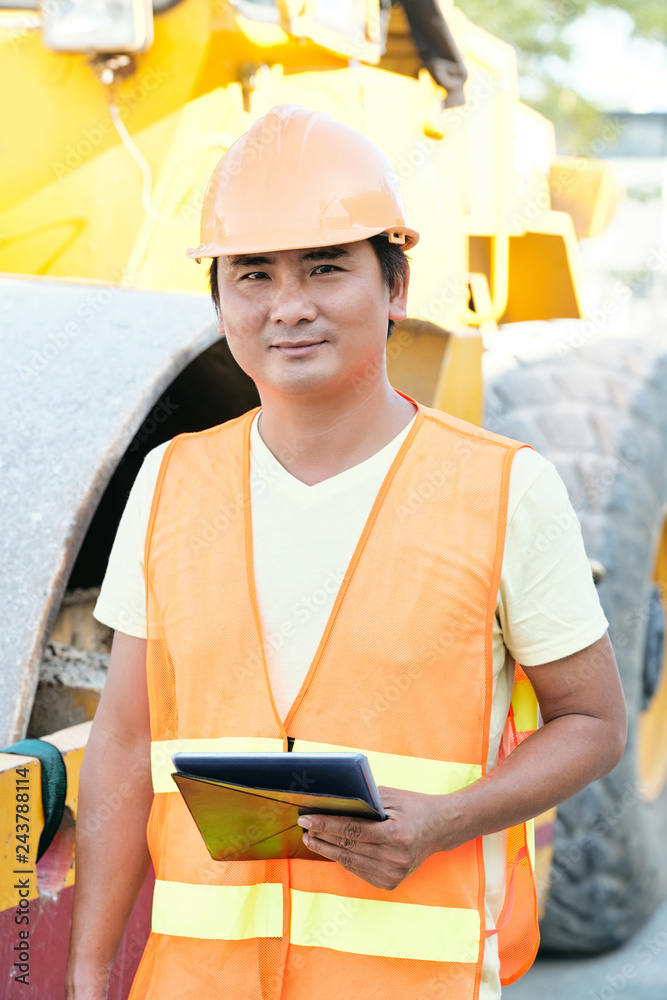 Fototapeta premium Smiling Asian construction worker with tablet computer working at construction site