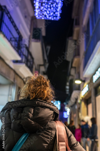 A tourist woman walking along the old streets of the old city of Plasencia, with Christmas lights during holidays making shopping and looking for gifts 