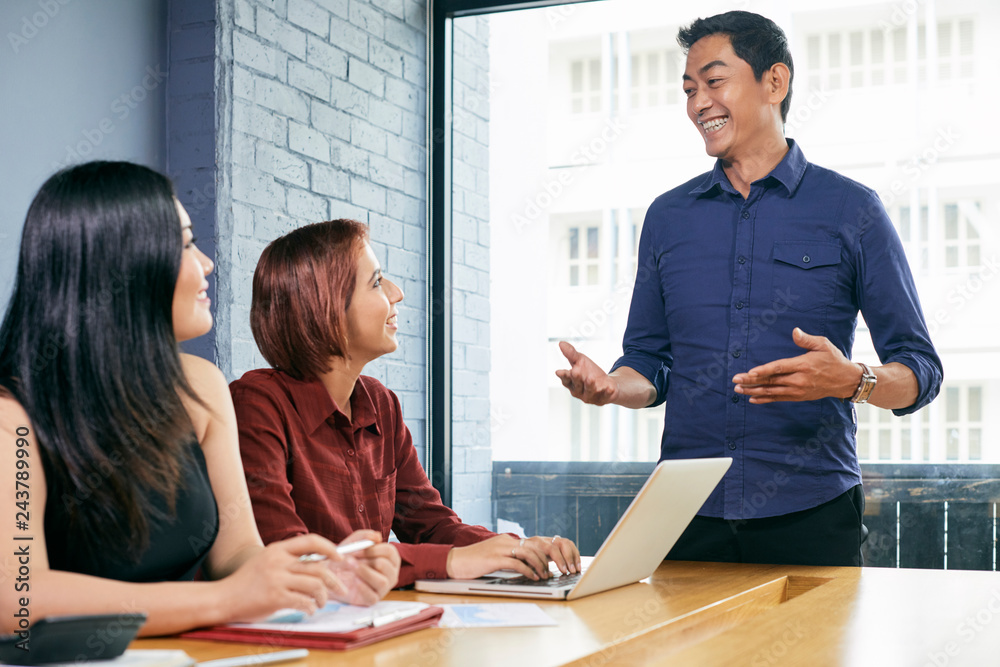Mature Asian entrepreneur conducting daily brainstorming session with coworkers Mature Asian entrepreneur conducting daily brainstorming session with coworkers