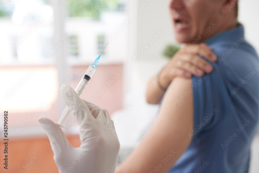 Male patient scared of sharp syringe needle in hand of doctor Male patient scared of sharp syringe needle in hand of doctor