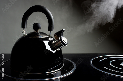 Kettle standing on the stove. Steam comes from the spout