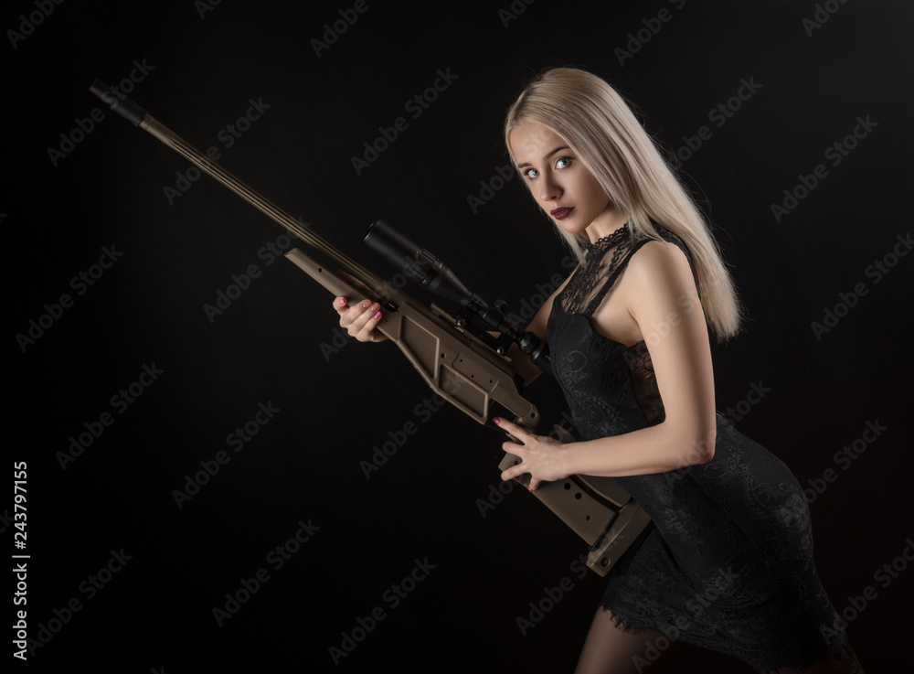 young blonde girl in black dress posing on black background with weapon young blonde girl in black dress posing on black background with weapon