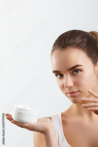 Fototapeta Naklejka Na Ścianę i Meble -  Beauty Concept. woman holds a cream in her hand and spreads it on her face to moisturize her skin and wrinkle from impurities. body care, skincare.Taking good care of her skin