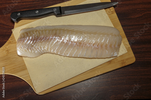 Raw cod fillet on a cutting board. Healthy eating. photo