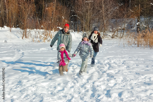 Happy family walks in winter, having fun and playing with snow outdoors on holiday weekend 