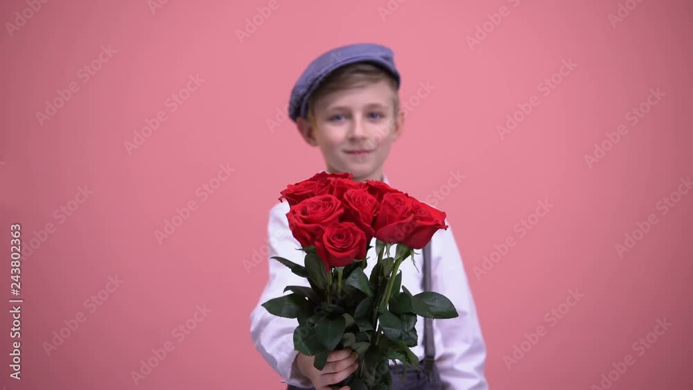 Cute gentleman boy presenting bouquet of red roses into camera, Valentines day Cute gentleman boy presenting bouquet of red roses into camera, Valentines day