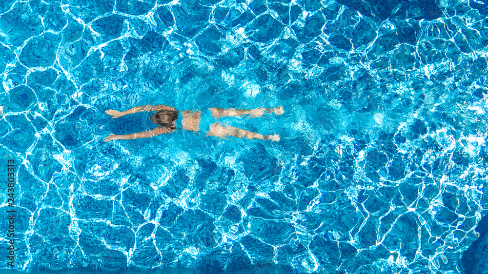 Active girl in swimming pool aerial drone view from above, young woman swims in blue water, tropical vacation, holiday on resort concept
