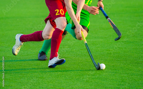 Two man battle for control of ball during field hockey game