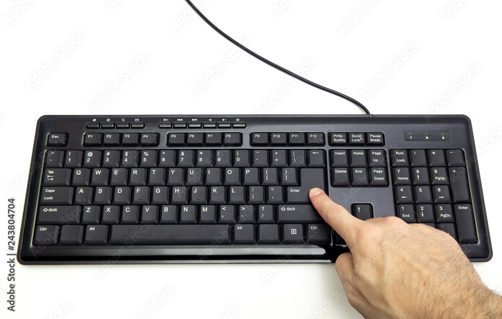 Finger pressing Enter button on the black keyboard Finger pressing Enter button on the black keyboard
