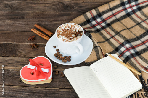 Cup of cappuccino, heart shaped cookies width message, notebook and checkered plaid on a brown wooden table