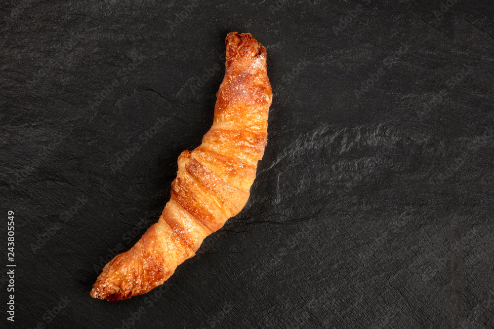 A photo of a croissant on a black background, shot from above with copy space A photo of a croissant on a black background, shot from above with copy space