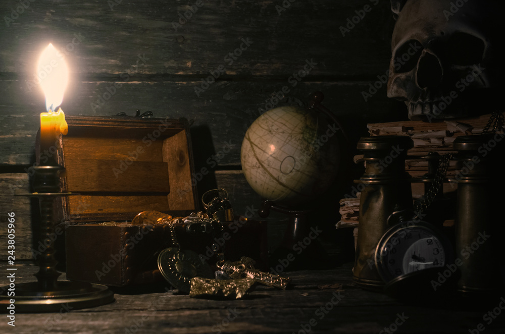 Pirate treasure chest with a gold on a pirate captain table in the light of burning candle background.