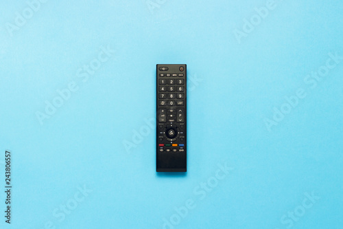 Black remote control on a blue background. The concept of television, movies, TV shows, sports. Flat lay, top view