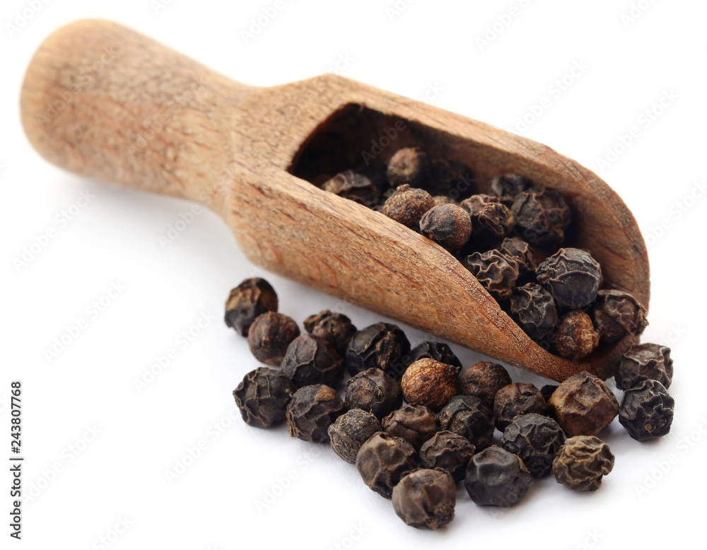 Black peppers on wooden scoop Black peppers on wooden scoop