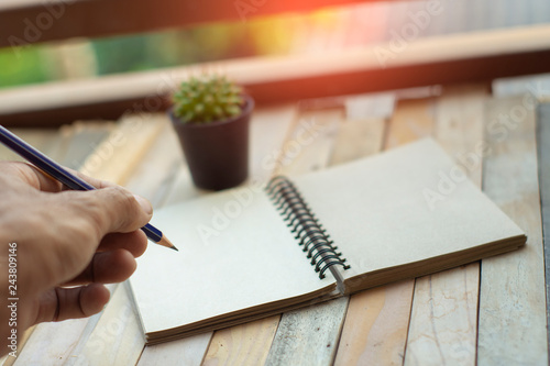 Notepad with pencil on wood board background. photo