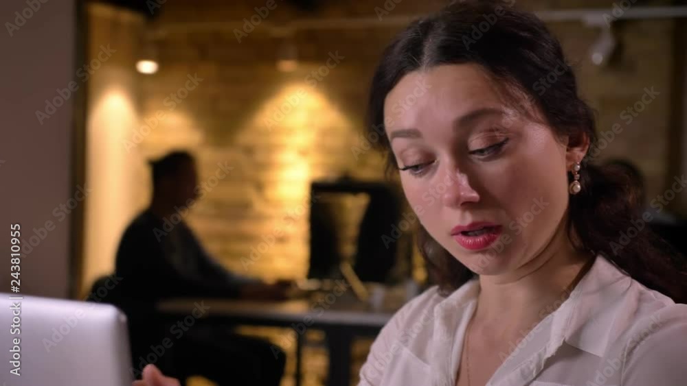 Closeup of young overworking female office worker getting a heache and being devastated and confused Closeup of young overworking female office worker getting a heache and being devastated and confused
