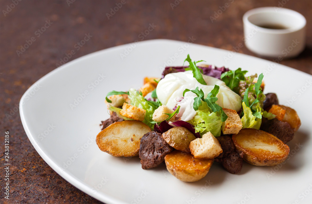 Warm salad with chicken, grilled potatoes, crackers, arugula, grated cheese and poached egg on a white plate and soy dressing. Close up. Selective focus. The concept of the menu. Warm salad with chicken, grilled potatoes, crackers, arugula, grated cheese and poached egg on a white plate and soy dressing. Close up. Selective focus. The concept of the menu.