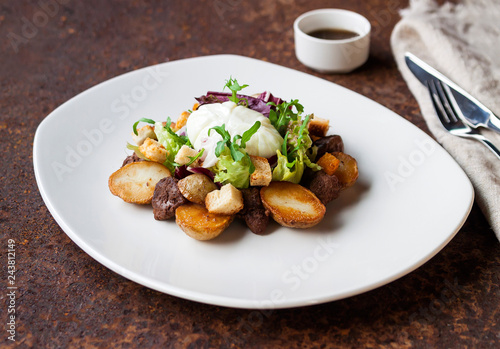 Warm salad with chicken, grilled potatoes, crackers, arugula, grated cheese and poached egg on a white plate and soy dressing. Close up. Selective focus. The concept of the menu. photo