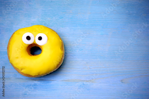 Yellow tasty donut lies on a wooden table